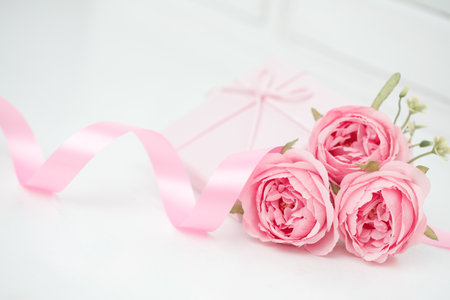 Three pink roses with ribbon and giftbox on the white table. Valentines day conceptの写真素材