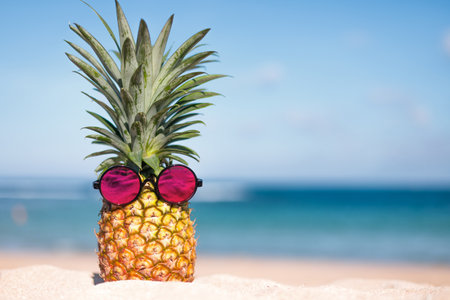 Two pineapples with trendy sunglasses on the beachの写真素材
