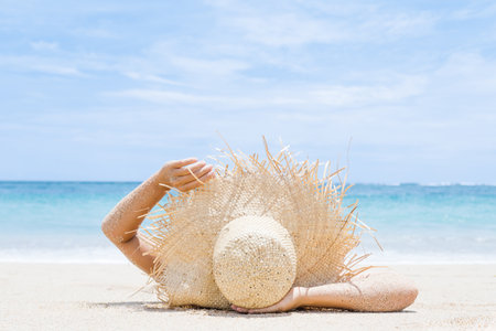 Woman lies on the white sand on the beachの写真素材
