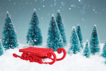 Red sled rests on snowy ground near pine treesの写真素材
