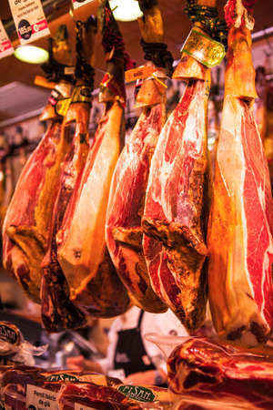 BARCELONA, SPAIN - OCTOBER 16, 2016: Jamon Serrano legs hanging from the ceiling in La Boqueria...