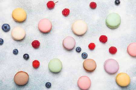 Variety of colorful french sweet dessert - makaron ( les macarons) with autumn flowers and berries.の写真素材