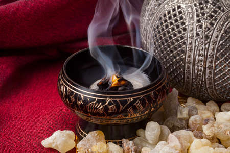 Frankincense burning on a hot coal. Frankincense is an aromatic resin, used for religious rites,...