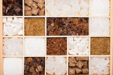 Various kinds of sugar in a wooden box. White refined, brown cane sugar collection