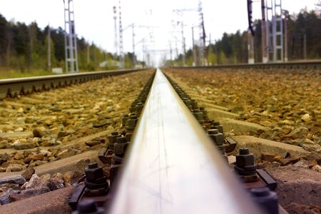 The railway rail with electric supports going into the distanceの写真素材