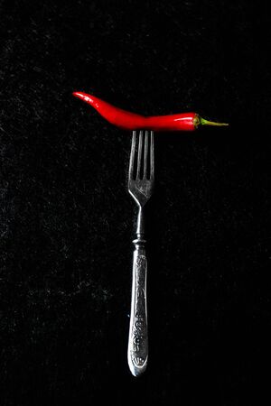Metal fork with pepper on a dark backgroundの写真素材
