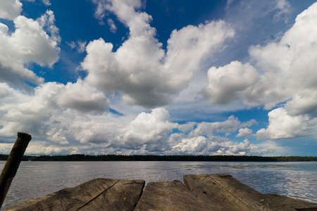 Wooden bridge on the river against the background of cloudsの写真素材