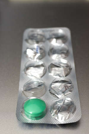 Empty pill box with one green pill