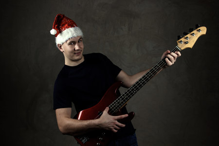 Young man in a New Years cap with a guitar. Holiday. Grey backgroundの写真素材