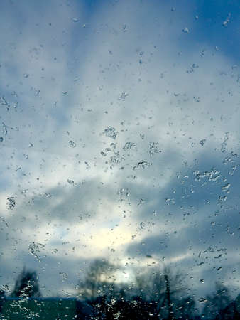 Ice on the glass of the car against the background of gray clouds. Vertical photo
