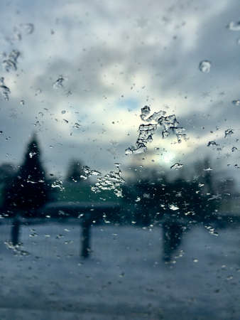 Ice on the glass of the car against the background of gray clouds. Vertical photo