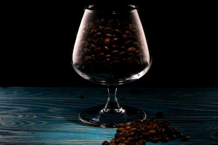 Coffee beans in a glass on a blue wooden tableの写真素材