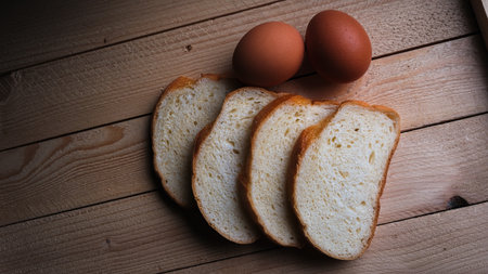 Pieces of bread on a wooden table with chicken eggsの写真素材