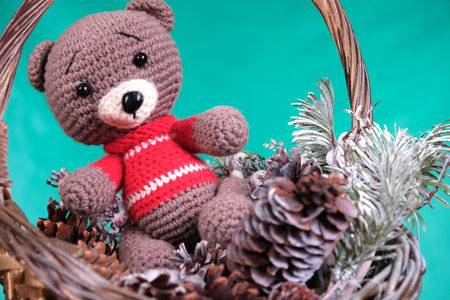 Toy bear in a Christmas basket with cones and a Christmas treeの写真素材