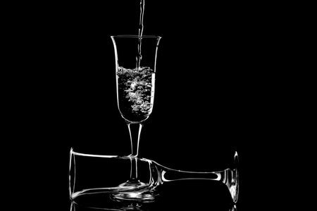 Water is poured into a glass on a glass table with reflectionの写真素材
