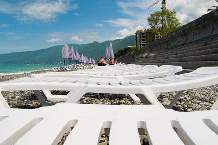 Abkhazia Gagra 06.06.2023 Sunbeds for relaxation with umbrellas on a rocky shore by the seaのeditorial素材