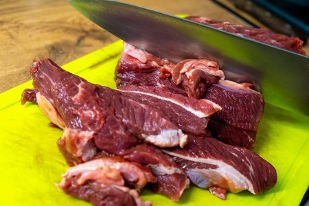 A display of freshly cut meat on a chopping board with a sharp knife nearby, ready to prepareの写真素材