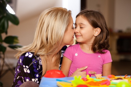 lovely little girl and her mother cuddling after playingの写真素材