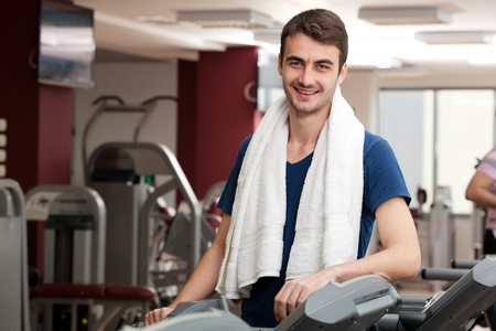 young man training in the gym, smiling, with towel around his neckの写真素材