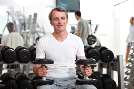 man training in the gym, smiling, holding dumbbells, preparing to do biceps or shouldersの写真素材