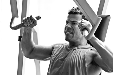 artistic shot, black and white, of a young bodybuilder hard training in the gym  incline chest press