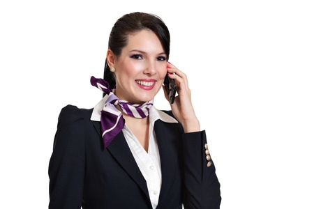 Beautiful dark haired young business woman dressed in a dark blue suit with a purple scarf smiling and talking to desktop phone held in her left hand, isolated on white backgroundの写真素材