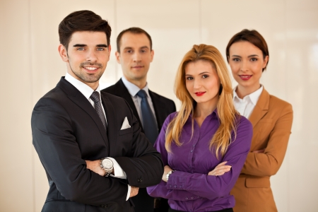 Four young business people, two men and two women, smiling  with their arms crossedの写真素材