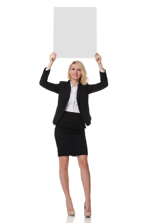 full length of a beautiful young blonde woman standing and holding up a boardの写真素材