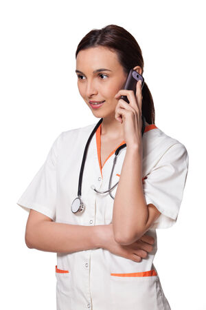beautiful young doctor with stethoscope, wearing white uniform, isolated on white background; nurse or medicine student talking on the phoneの写真素材