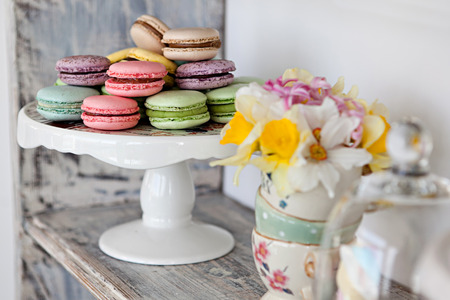 Coloured arrangement of macaroons and flowers on a wooden tableの写真素材