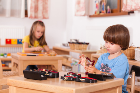 Child playing his toy harp at his table; Image shot from a kindergartenの写真素材