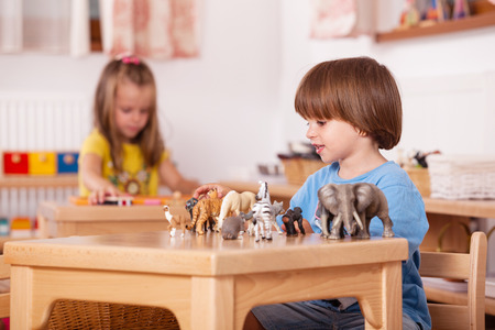 Child playing with his animal toys at his table; Image shot from a kindergartenの写真素材
