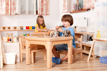 Child playing with his animal toys at his table; Image shot from a kindergartenの写真素材