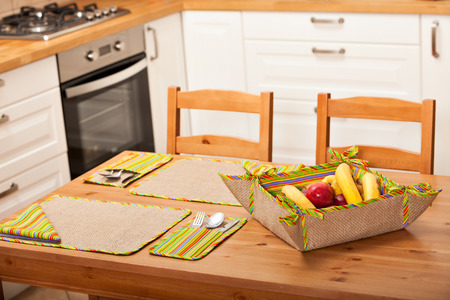 Elegant kitchen table setting with striped pattern fabrics and a bowl of bananas and applesの写真素材