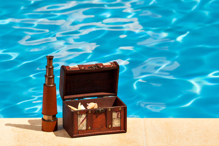 Concept background summer pool image shot of a trunk filled with shells and a telescope, copy spaceの写真素材