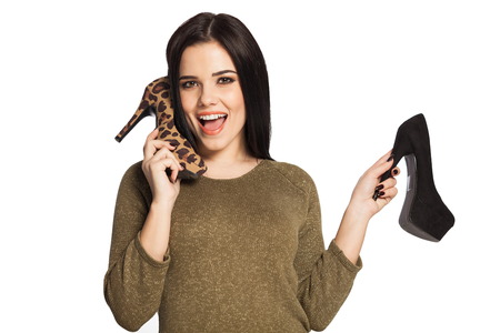 Surprised woman holding a shoe next to her ear, pretending to talk. Gorgeous white caucasian female model isolated on white background.の写真素材