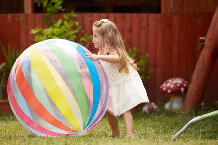 happy blonde girl playing with a big ballの写真素材