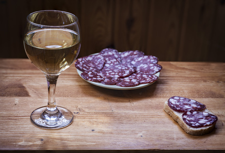 Wine Riesling in a glass and smoked sausage on a plate.の写真素材
