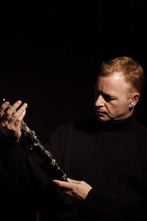 musician holding a clarinet isolated against black backgroundの写真素材