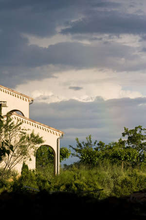 a stormy sky and rainbow over a houseの写真素材