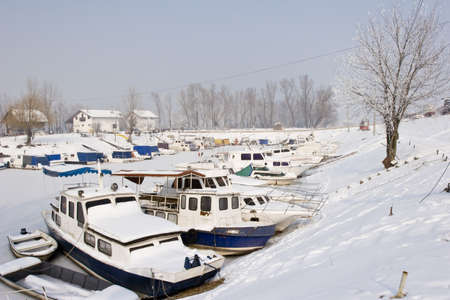 snow covered old boats in frozen marinaの写真素材