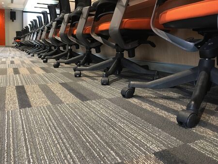 Modern patterned carpets in meeting rooms, seminar rooms, in contemporary buildings. Side view of office space with computer tables with chairs desktops standing on them.の写真素材