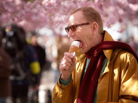 A man eats ice cream when the Japanese cherry trees blossom in the Royal park in Stockholm April 30, 2012のeditorial素材