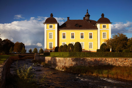 STROMSHOLM, SWEDEN: The yellow Swedish royal palace Stromsholm  (Str?olm) with blue sky with streams and moat in the foreground. Stromsholm palace is host to the annual horse race Swedidh Grand Nationalのeditorial素材
