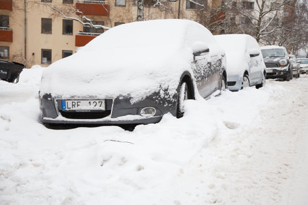 Stockholm, Sweden - December 20, 2012: Snow in parked cars on Furusundsgatan. A snow bank by a snowplow complicates driveway with the car.のeditorial素材