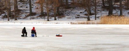 Two people ice fishing on a Swedish lake.のeditorial素材