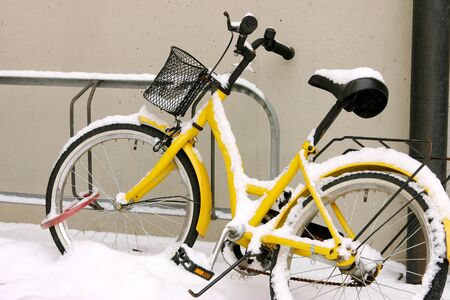 Yellow bike in the snow correctly finds the bike rack and leaning against the wall   の写真素材