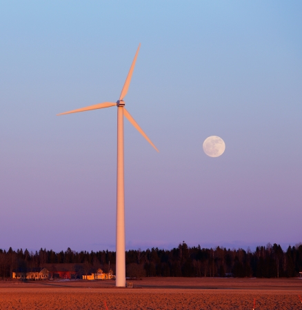 Small wind turbines in the Swedish countryside at dusk with full moon   の写真素材