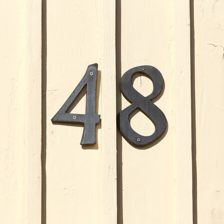 Street address number 48 on  a light yellow wooden wall.の写真素材