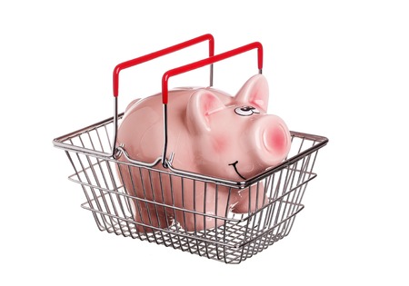One piggy bank in a shopping basket with red handles, isolated on white.